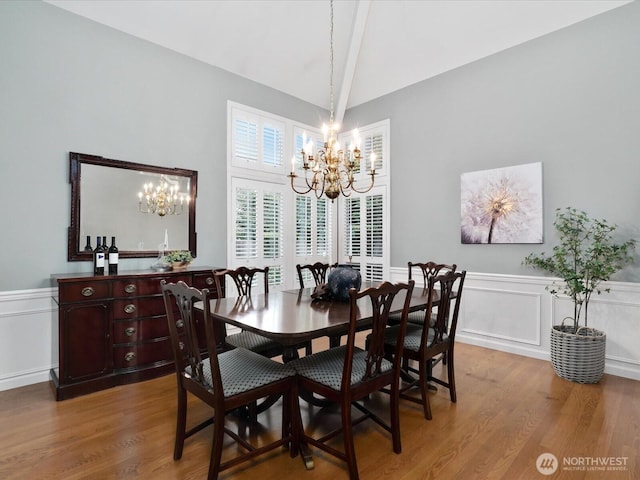 dining area with high vaulted ceiling, a wainscoted wall, a chandelier, and wood finished floors