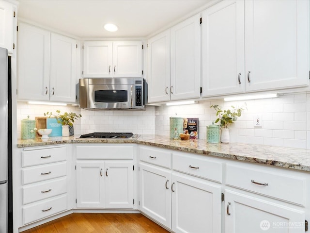 kitchen featuring white cabinetry, stainless steel appliances, and backsplash