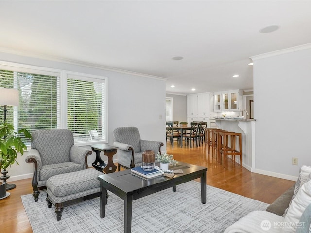 living room featuring ornamental molding, recessed lighting, baseboards, and wood finished floors