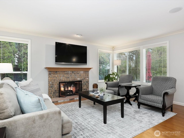 living room with crown molding, a brick fireplace, wood finished floors, and a healthy amount of sunlight