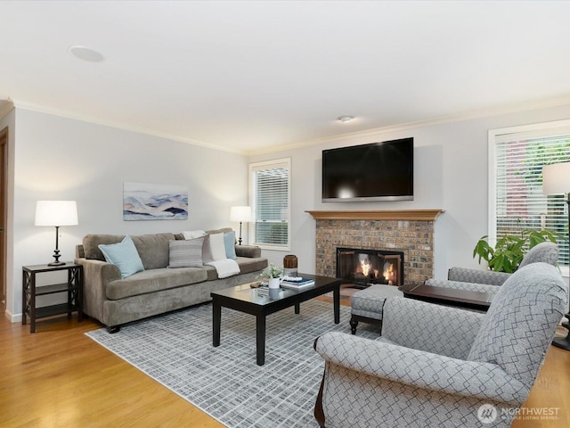 living area featuring light wood-type flooring, a fireplace, and crown molding