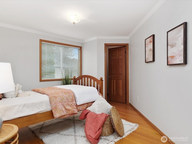 bedroom with light wood-style floors, crown molding, and baseboards