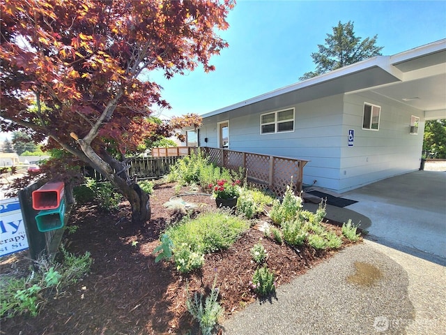 view of side of home featuring driveway, an attached carport, and fence