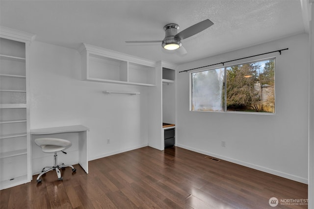 unfurnished office featuring baseboards, a textured ceiling, visible vents, and wood finished floors