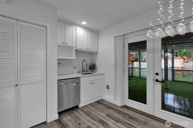 kitchen with french doors, stainless steel dishwasher, white cabinets, a sink, and light wood-type flooring