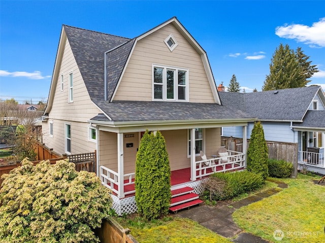 view of front of property with a gambrel roof, a front lawn, fence, covered porch, and a shingled roof