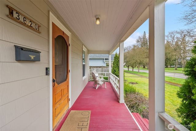 view of exterior entry with a yard and a porch