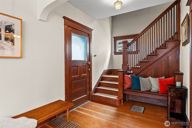 entrance foyer with stairway, wood finished floors, visible vents, and arched walkways