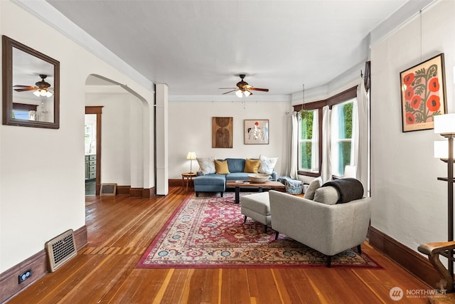 living room featuring visible vents, arched walkways, hardwood / wood-style floors, and crown molding