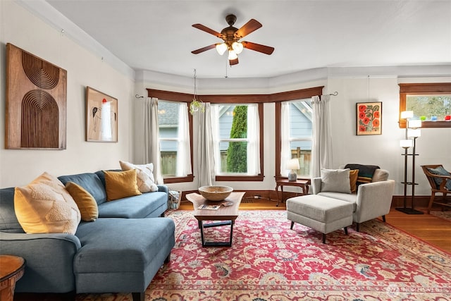 living area featuring ceiling fan, baseboards, a healthy amount of sunlight, and wood finished floors