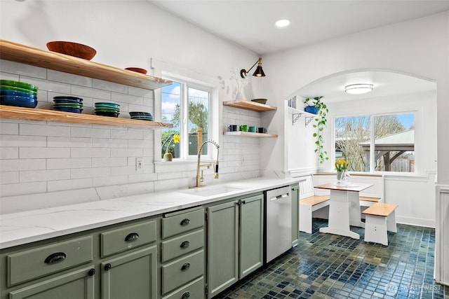 kitchen with a sink, open shelves, arched walkways, green cabinets, and dishwasher