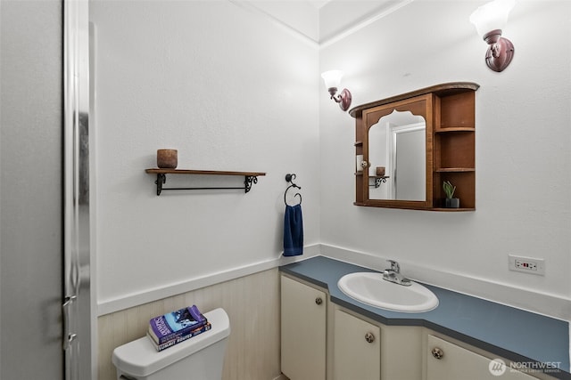 half bath featuring toilet, wainscoting, and vanity