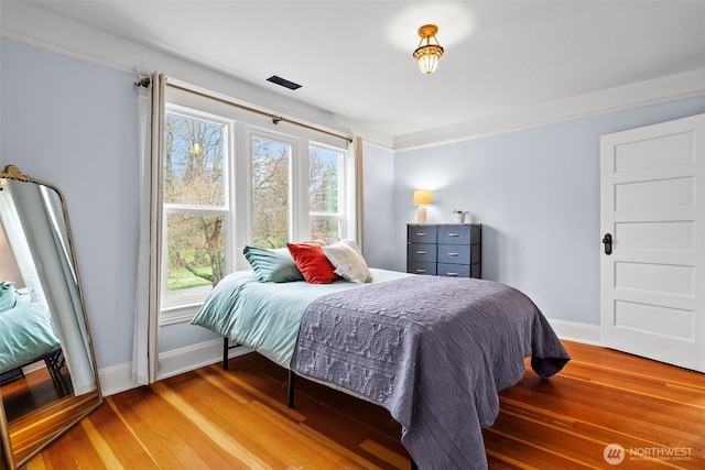 bedroom featuring light wood finished floors and baseboards