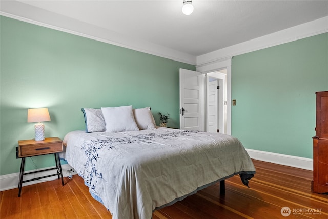 bedroom with baseboards, wood finished floors, and crown molding