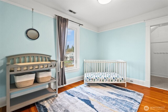 bedroom featuring visible vents, baseboards, and wood finished floors