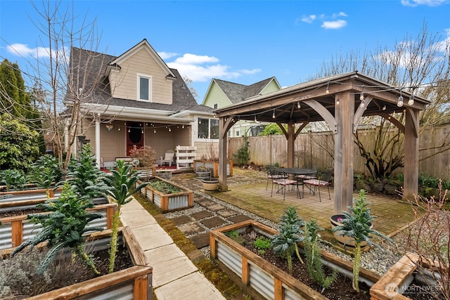 view of patio featuring a gazebo, fence, and a garden