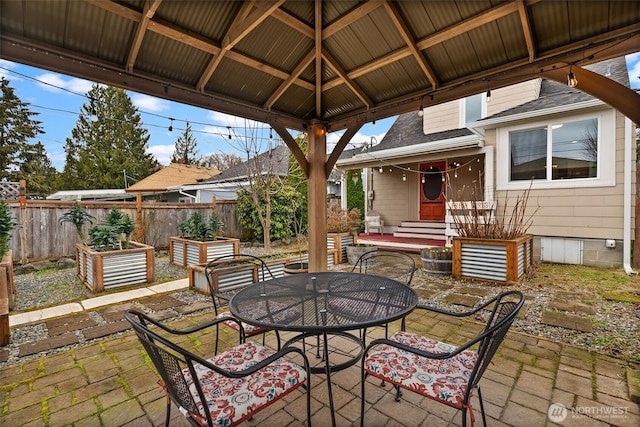 view of patio / terrace with a gazebo, fence, outdoor dining space, and entry steps