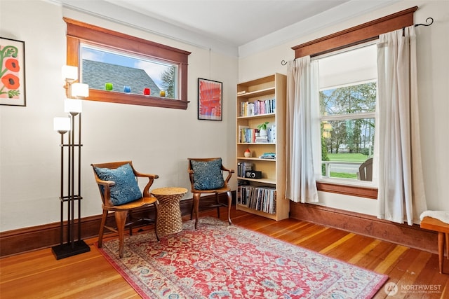 sitting room featuring crown molding, baseboards, and wood finished floors