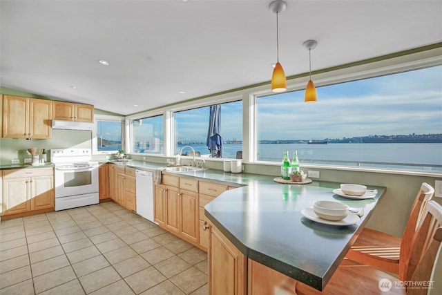 kitchen featuring light tile patterned floors, light brown cabinetry, a sink, white appliances, and a peninsula