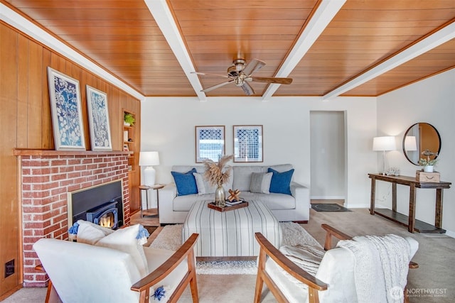 living area featuring beamed ceiling, wooden ceiling, a ceiling fan, and light colored carpet