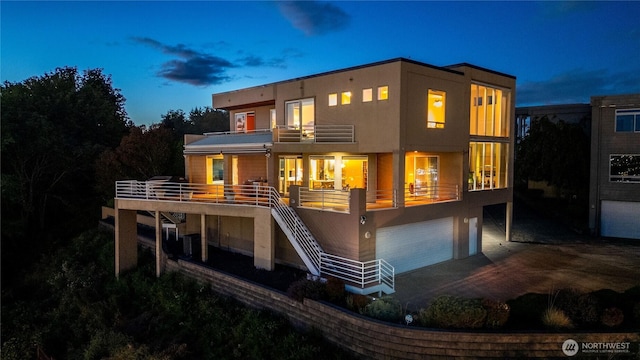 rear view of house featuring an attached garage, stairway, a balcony, and stucco siding