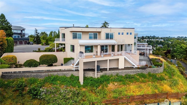 rear view of property with fence, stairway, cooling unit, and stucco siding