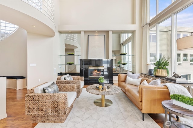 living area with a high ceiling and a glass covered fireplace