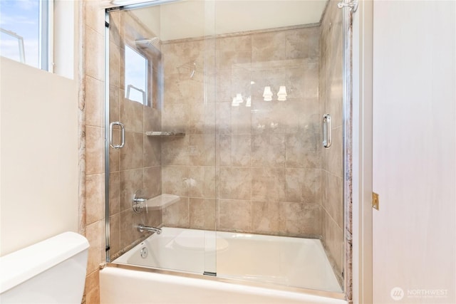 bathroom with combined bath / shower with glass door and toilet