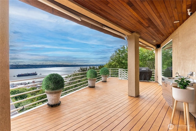 wooden terrace with a water view and area for grilling