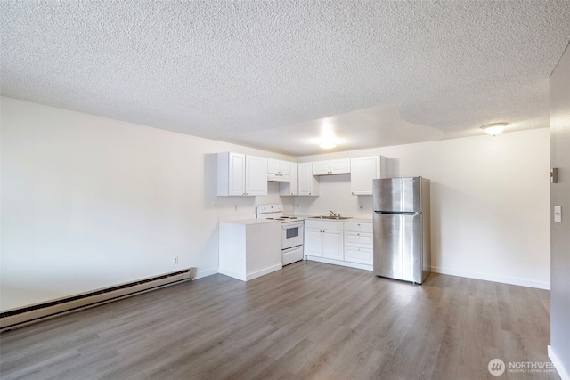 kitchen with a sink, wood finished floors, baseboard heating, freestanding refrigerator, and white range with electric cooktop