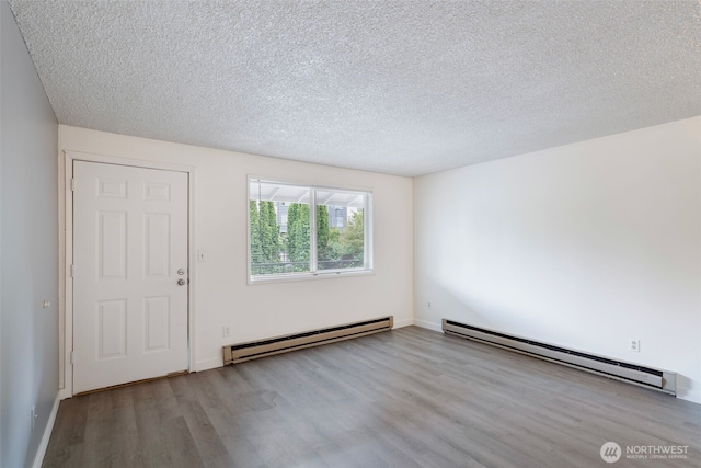 empty room with a baseboard heating unit, a textured ceiling, and wood finished floors