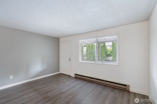 spare room with a textured ceiling, baseboards, baseboard heating, and wood finished floors