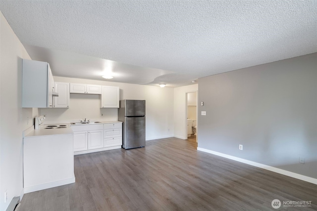 kitchen featuring range, freestanding refrigerator, light countertops, a baseboard heating unit, and a sink