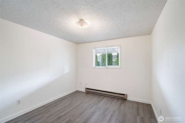 spare room featuring a baseboard radiator, a textured ceiling, baseboards, and wood finished floors