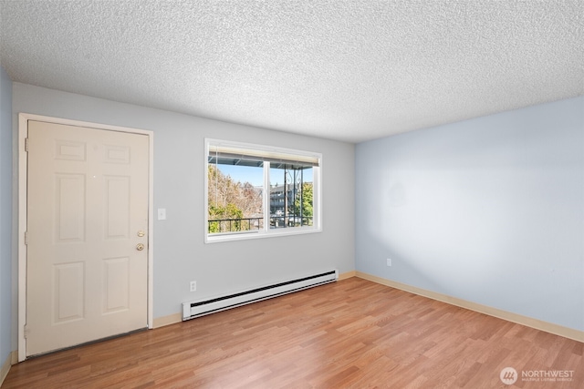 unfurnished room with light wood finished floors, baseboard heating, and a textured ceiling