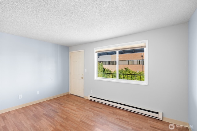 unfurnished room with baseboards, a textured ceiling, a baseboard heating unit, and wood finished floors