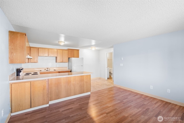 kitchen featuring freestanding refrigerator, light countertops, range with electric cooktop, and a peninsula