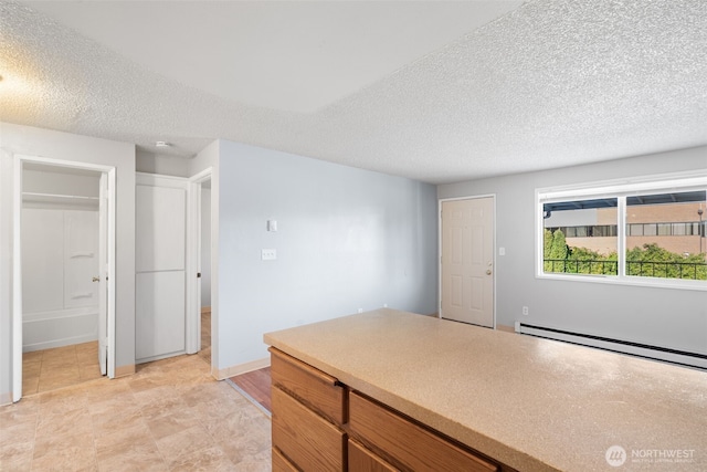 kitchen featuring brown cabinetry, light countertops, a textured ceiling, and baseboard heating