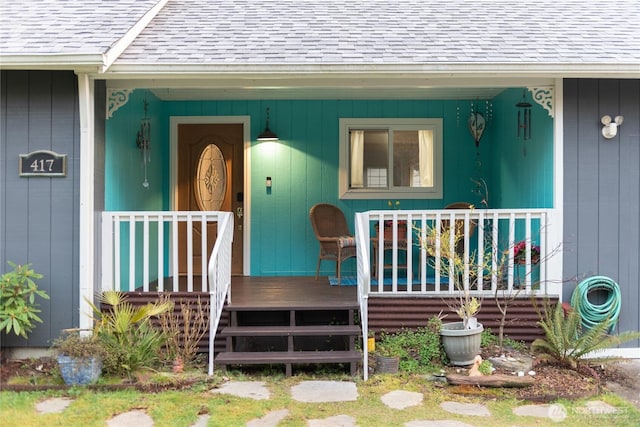 doorway to property with a porch and roof with shingles