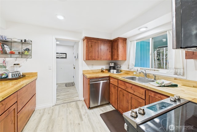 kitchen featuring a sink, wooden counters, appliances with stainless steel finishes, light wood finished floors, and brown cabinetry