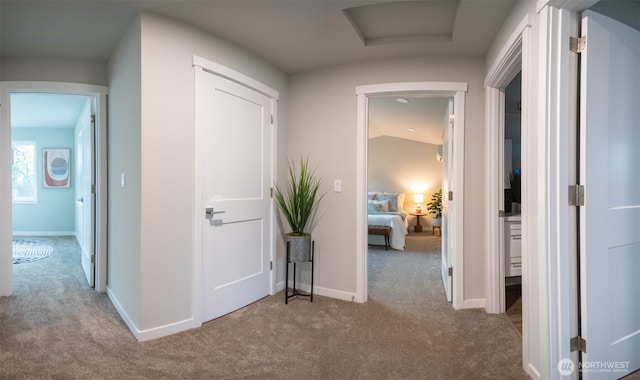 hall with carpet floors, attic access, and baseboards