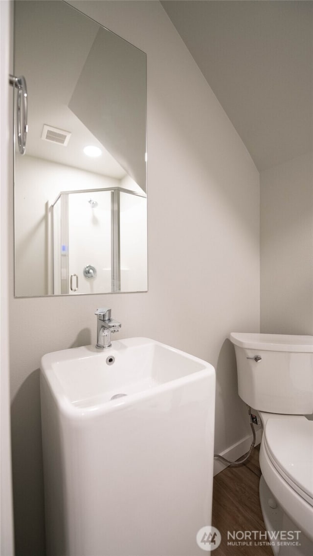 bathroom featuring toilet, visible vents, a sink, and wood finished floors