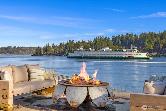 view of water feature featuring an outdoor fire pit and a wooded view