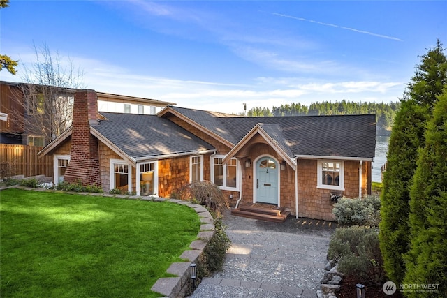 view of front of home featuring a shingled roof, a chimney, and a front yard