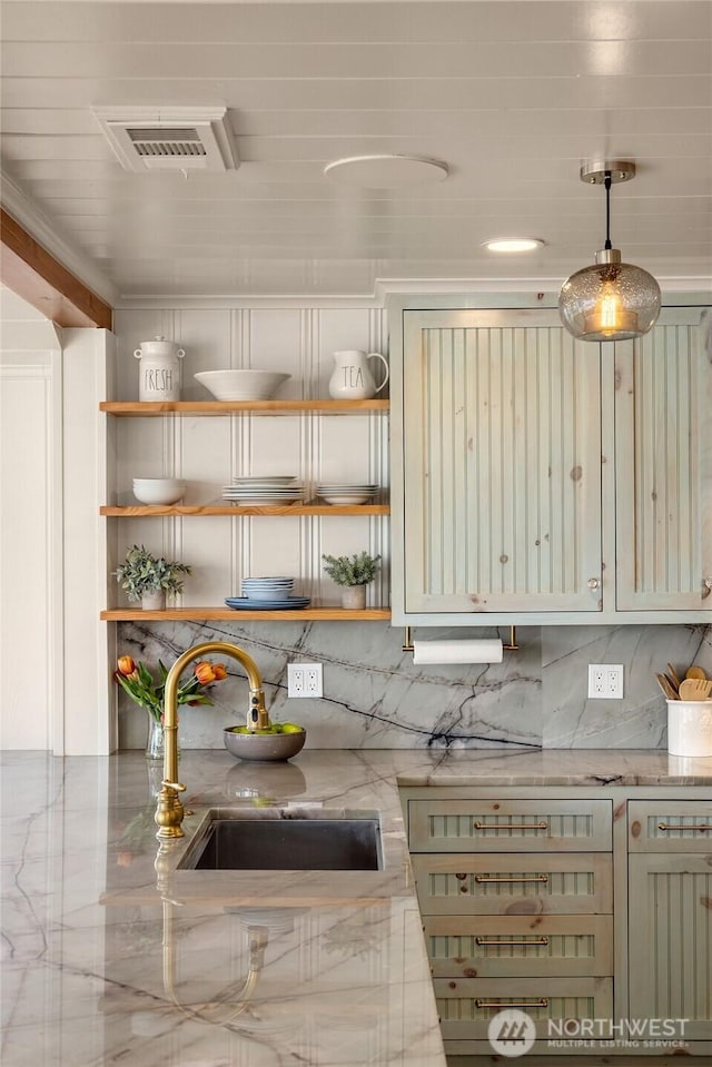 kitchen featuring visible vents, light stone counters, a sink, open shelves, and backsplash