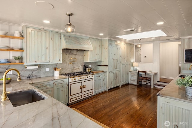 kitchen featuring light stone counters, range with two ovens, a sink, decorative backsplash, and custom range hood