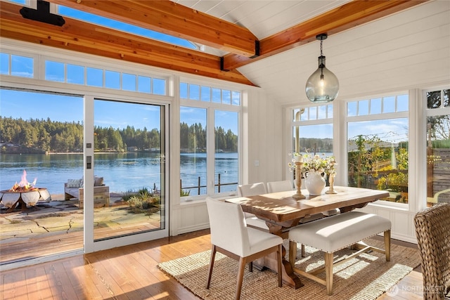 sunroom / solarium featuring a water view and vaulted ceiling with beams