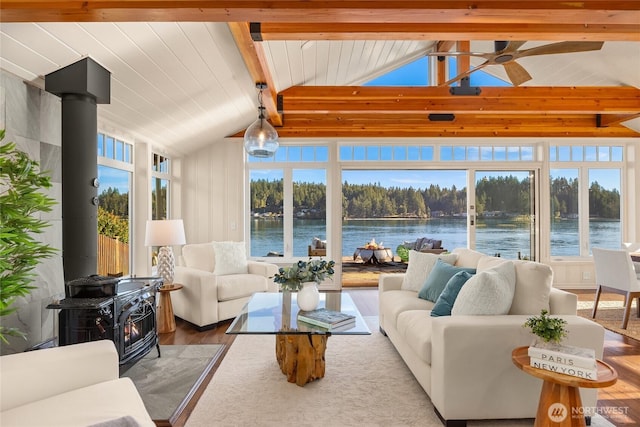 sunroom / solarium with a wood stove, a healthy amount of sunlight, lofted ceiling with beams, and a water view