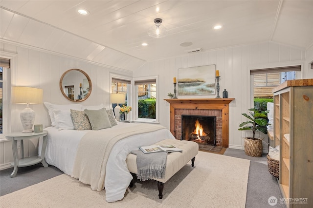 carpeted bedroom with a brick fireplace, visible vents, vaulted ceiling, and recessed lighting