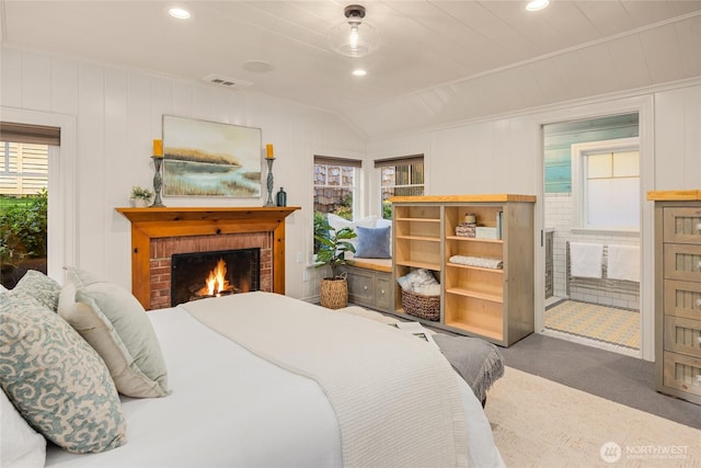 bedroom with lofted ceiling, a brick fireplace, multiple windows, and visible vents